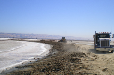 Large truck on the beach, working on the shoreline.